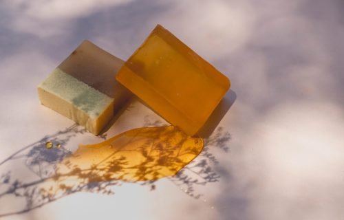Close-up of handmade soap bars under artistic lighting, showcasing natural ingredients and shadows.